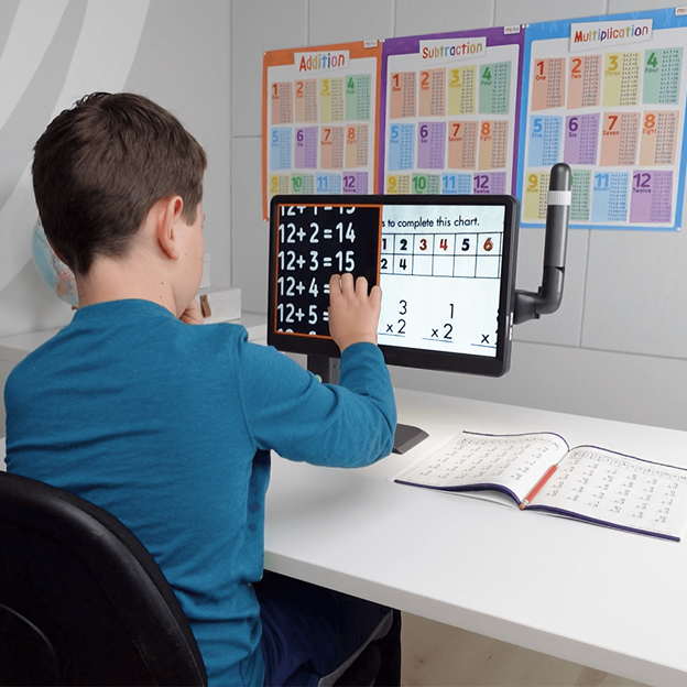 Student using MirrorPad Pro split-screen mode to view magnified math problems in the distance on the board in front of him and magnifying the worksheet on the tabletop simultaneously for easier problem solving.