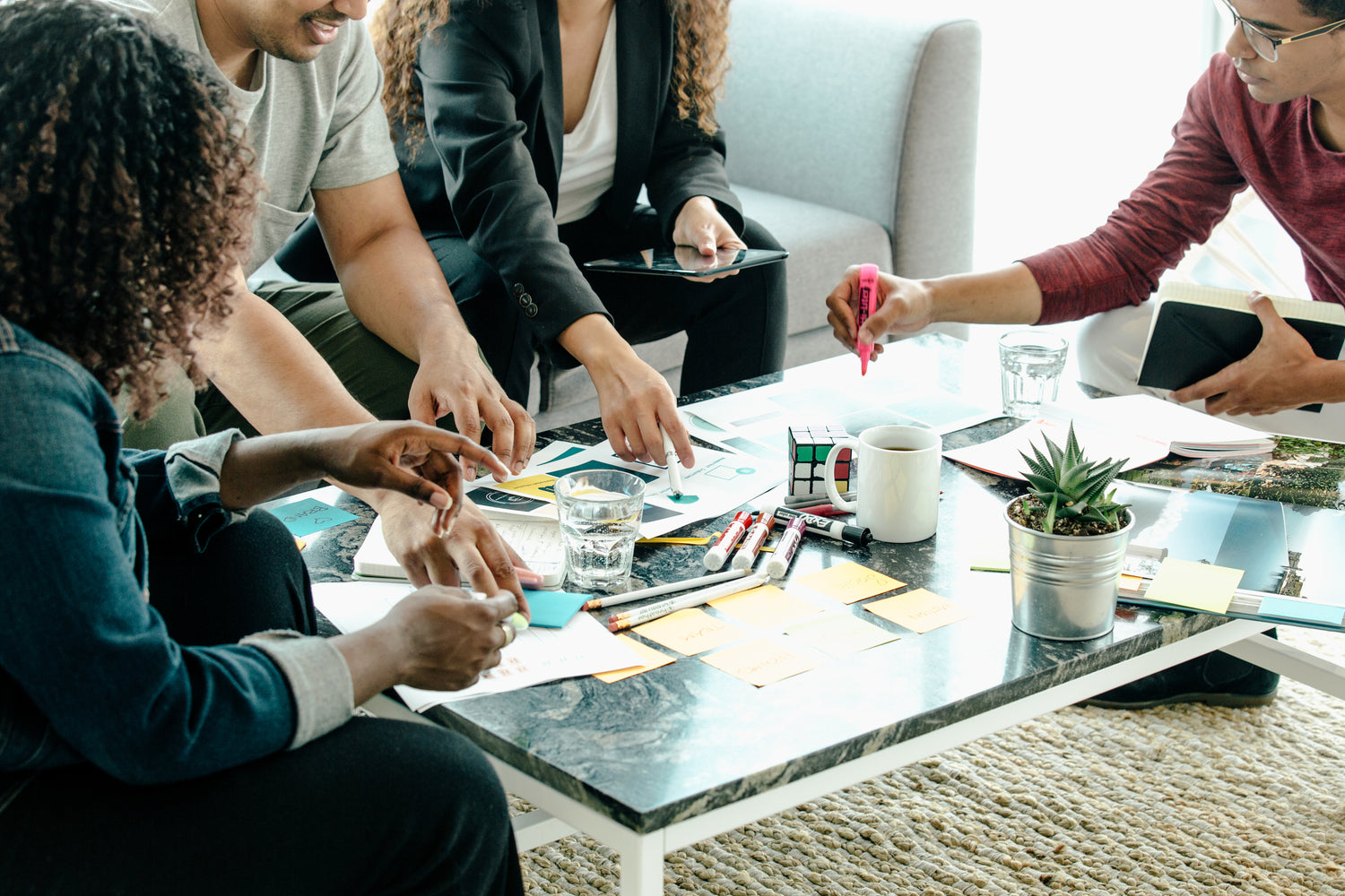 4 Individuals pointing to sheets of paper on a class coffee table