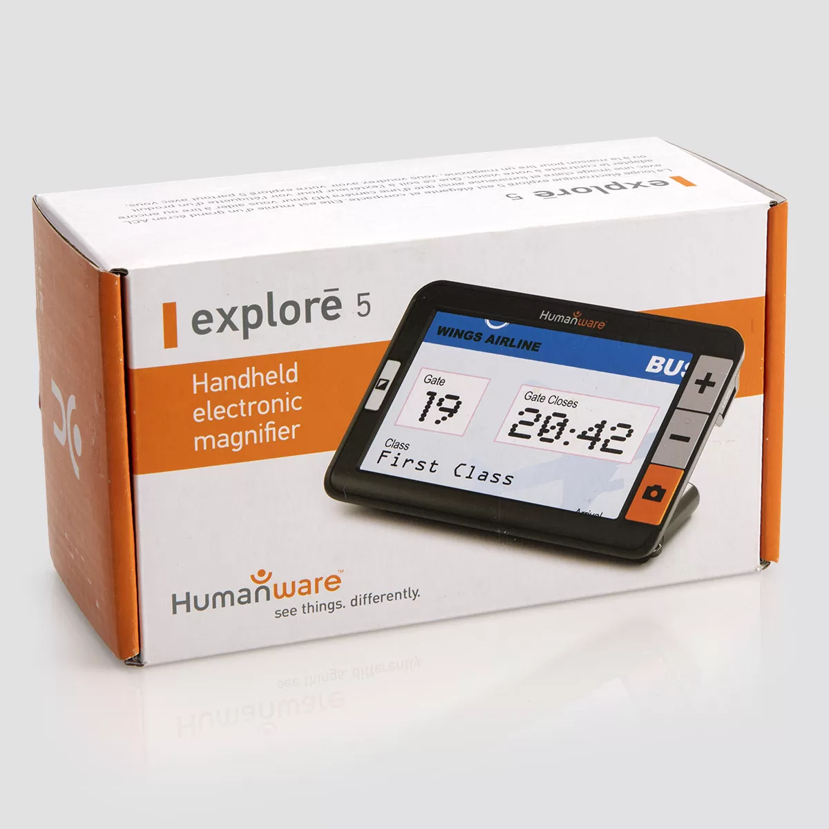 Humanware Explore 5 electronic magnifier in manufacturer packaging. The box is white and orange and features a close up of the device which features a high definition LCD screen with physical buttons that include a bright orange camera button and buttons to increase and decrease size. The device is angled and can stand up on its own for easy viewing.