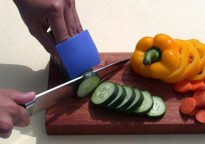 A person cutting a cucumber with a sharp knife and using a blue DigiFuard finger guard on their hand that is holding the cumber