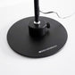The round black weighted base of the corded Magno Lumina Max Desk Lamp shown with tightening button to secure the base to the lamp neck.