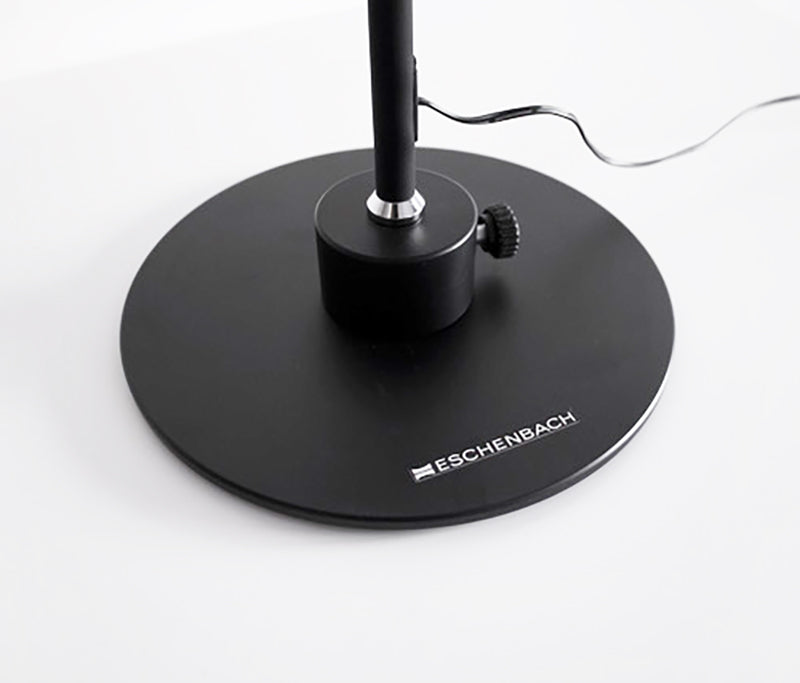 The round black weighted base of the corded Magno Lumina Max Desk Lamp shown with tightening button to secure the base to the lamp neck.