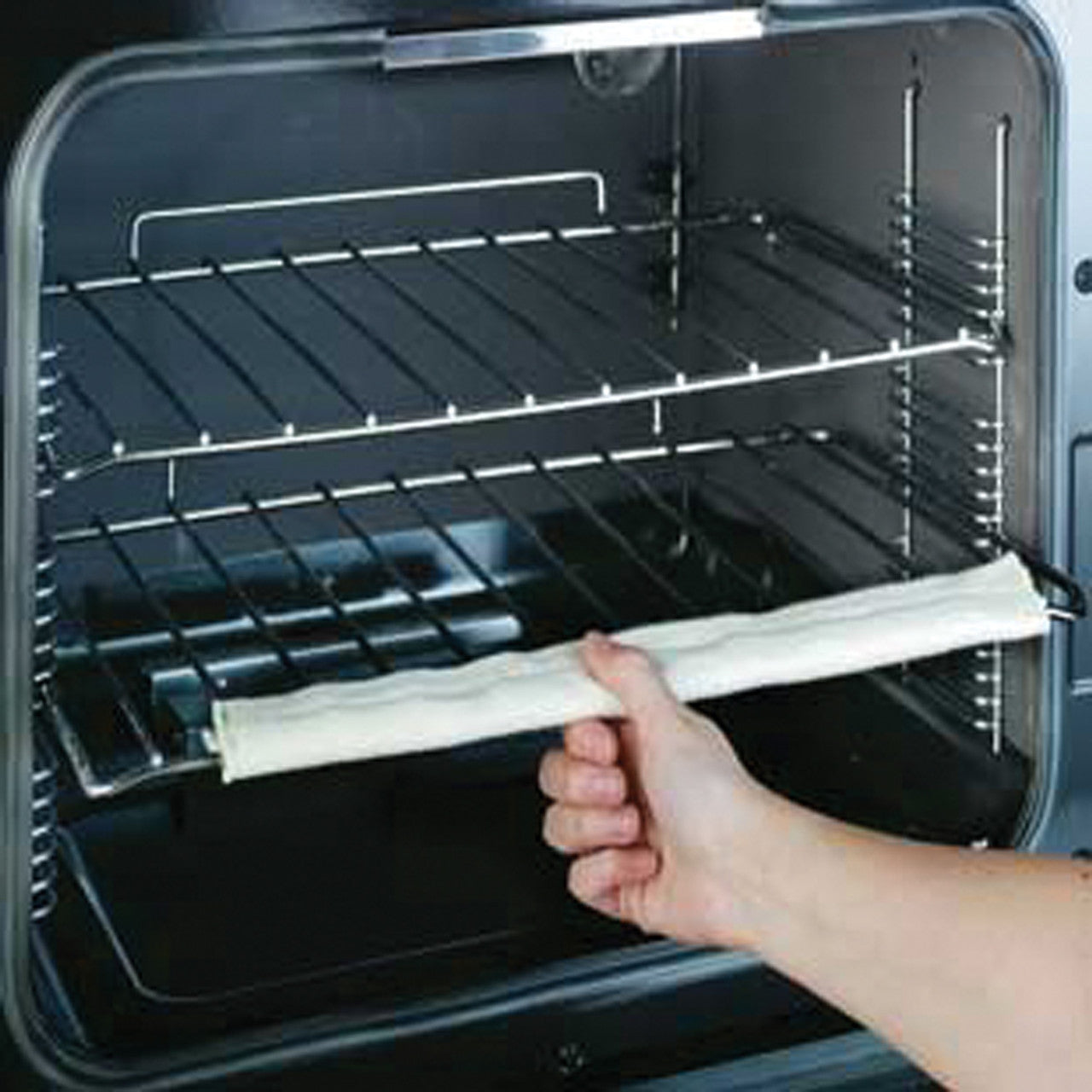 A single oven rack guard installed on an overn rack with a person pulling the rack out