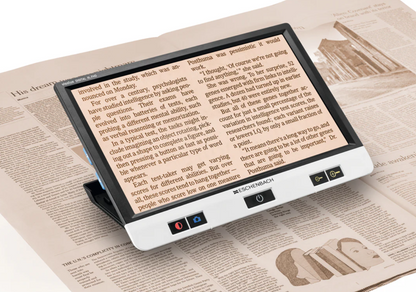 Eschenbach Visolux XL HD portable video magnifier enlarging newspaper text on its built-in screen.