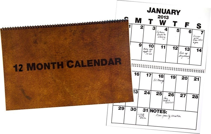 Large 12 Month Calendar for the Year. Calendar has front conver in brown with words 12 month calendar. A full view of the calendar open to the month of January with Bold black writing and lines.