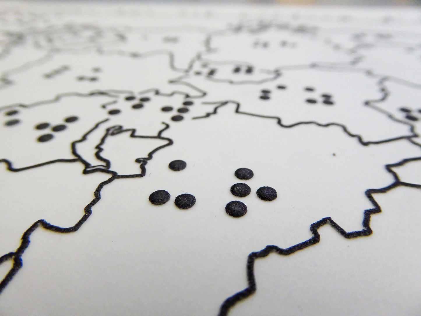Close up view of the Braille and Tactile World Map with black borders and black braille dots on a white background.