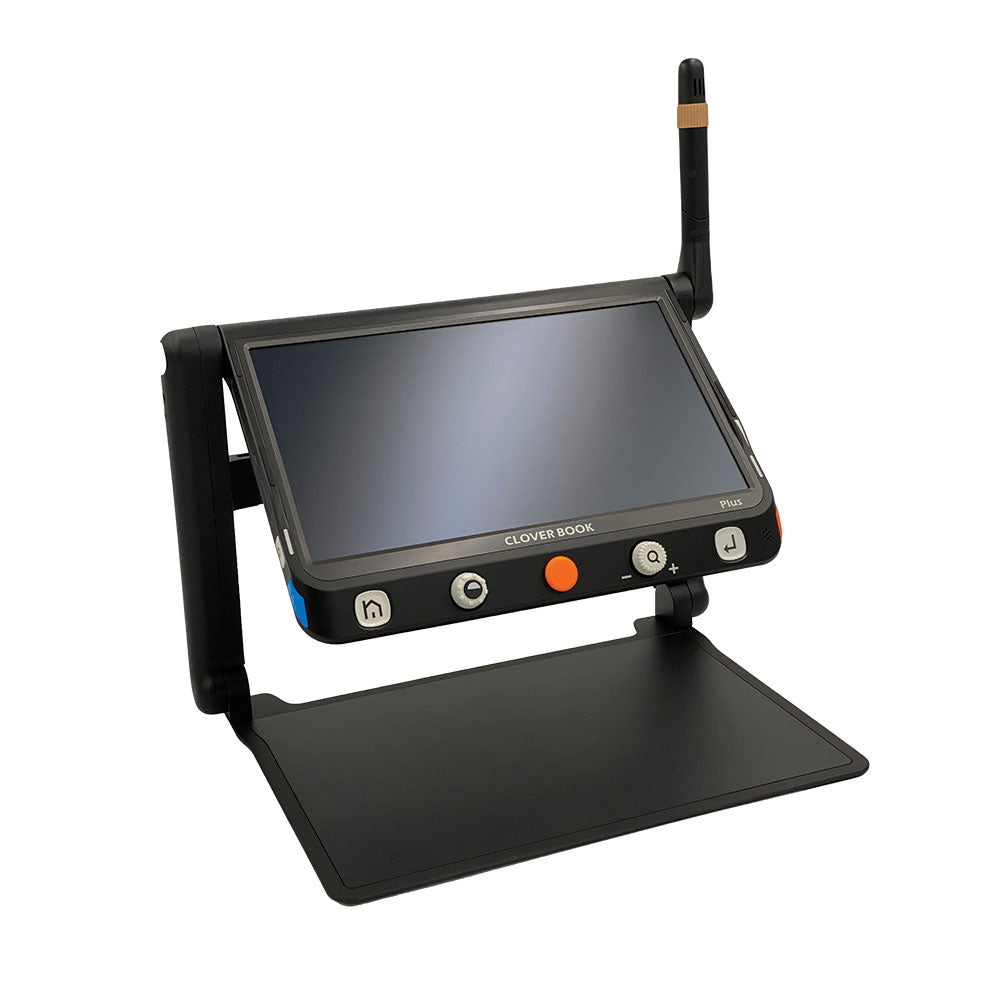 The Irie Cloverbook electronic magnifier in black for independent living. The device has a screen that is magnifying a photograph of a family of 4 underneath it. The screen is on a stable 2 legged, foldable stand and has 5 big buttons at the bottom of the device with an orange one in the middle.
