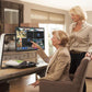 Two ladies siting and standing touching the screen of the Optelec ClearView C 24" HD CCTV