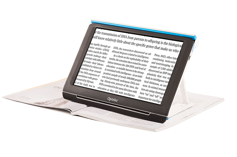 Front facing view of the portable Optelec Compact 10 With Speech displaying enlarged text on it's screen resting on top of an open magazine.  