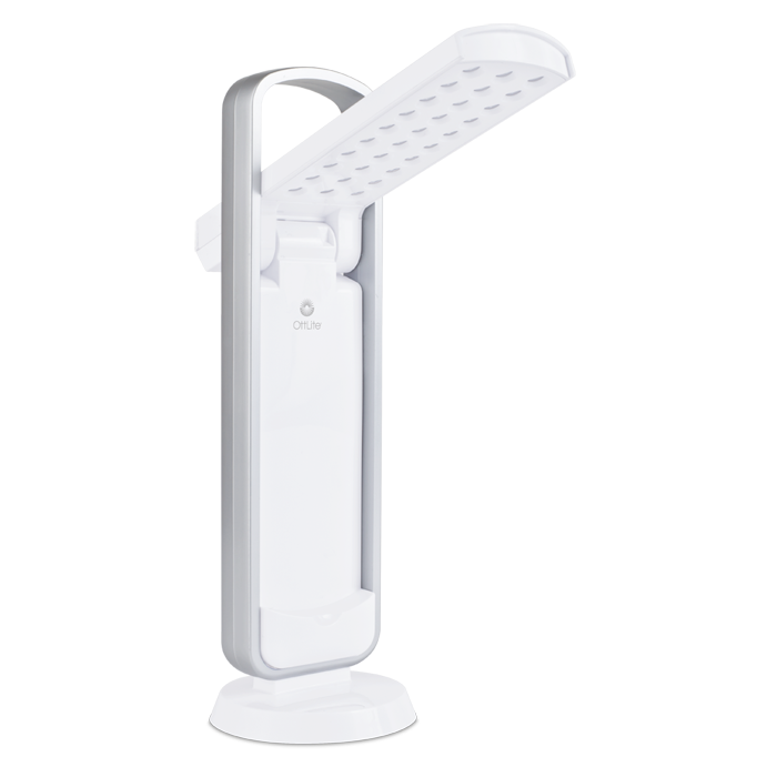 Task lamp in all white with silver handle above. LED lights are visible  on the open arm with the Ottlite logo visible. in the center