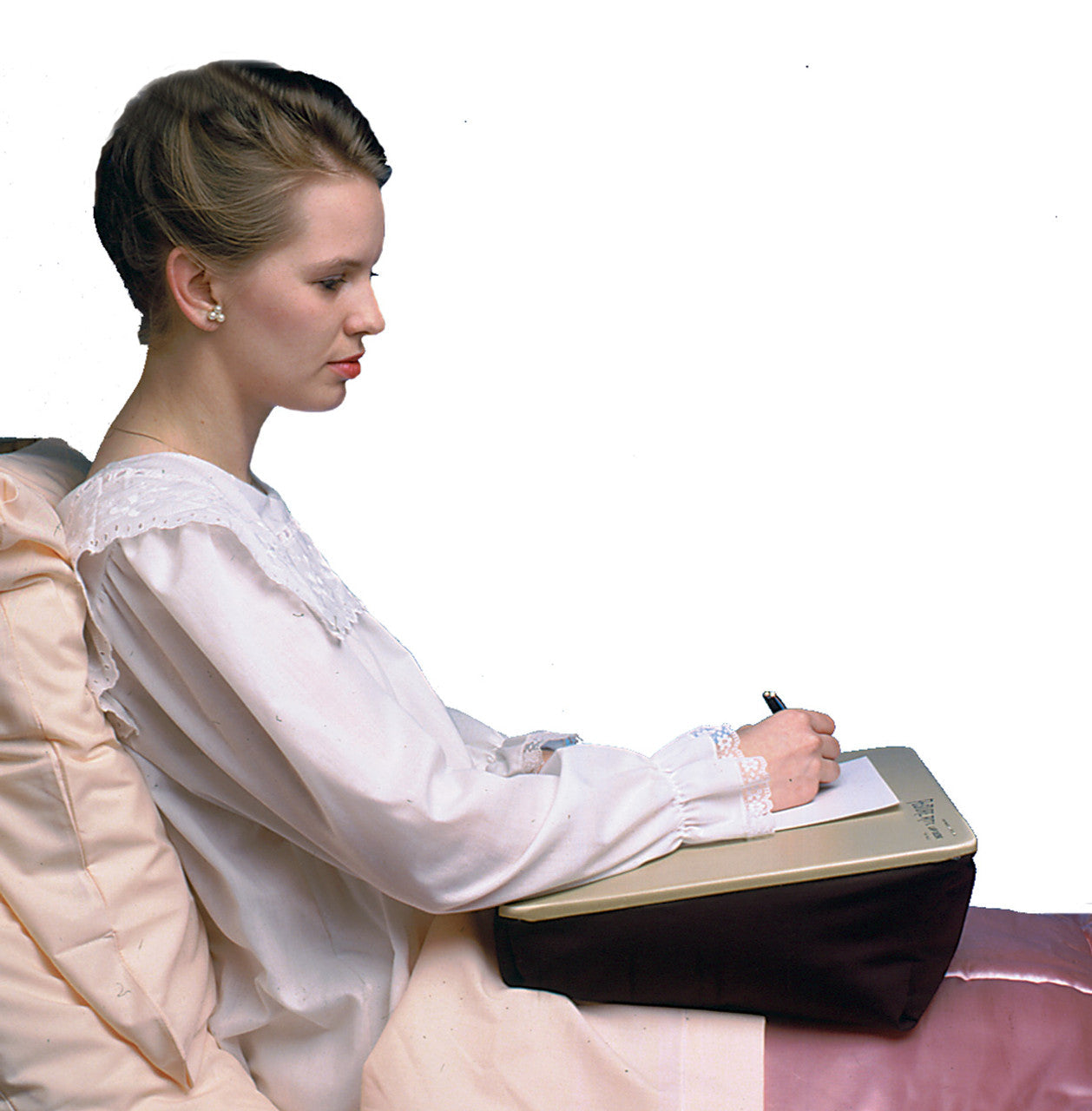 woman holding a pen writing on a piece of paper on top of her LapDesk